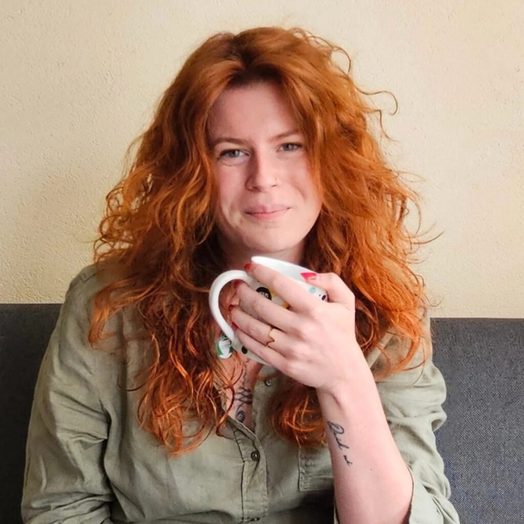 Foto van Nathalie de Groot. Ze houdt een mok vast en lacht naar de camera met een gesloten mond.